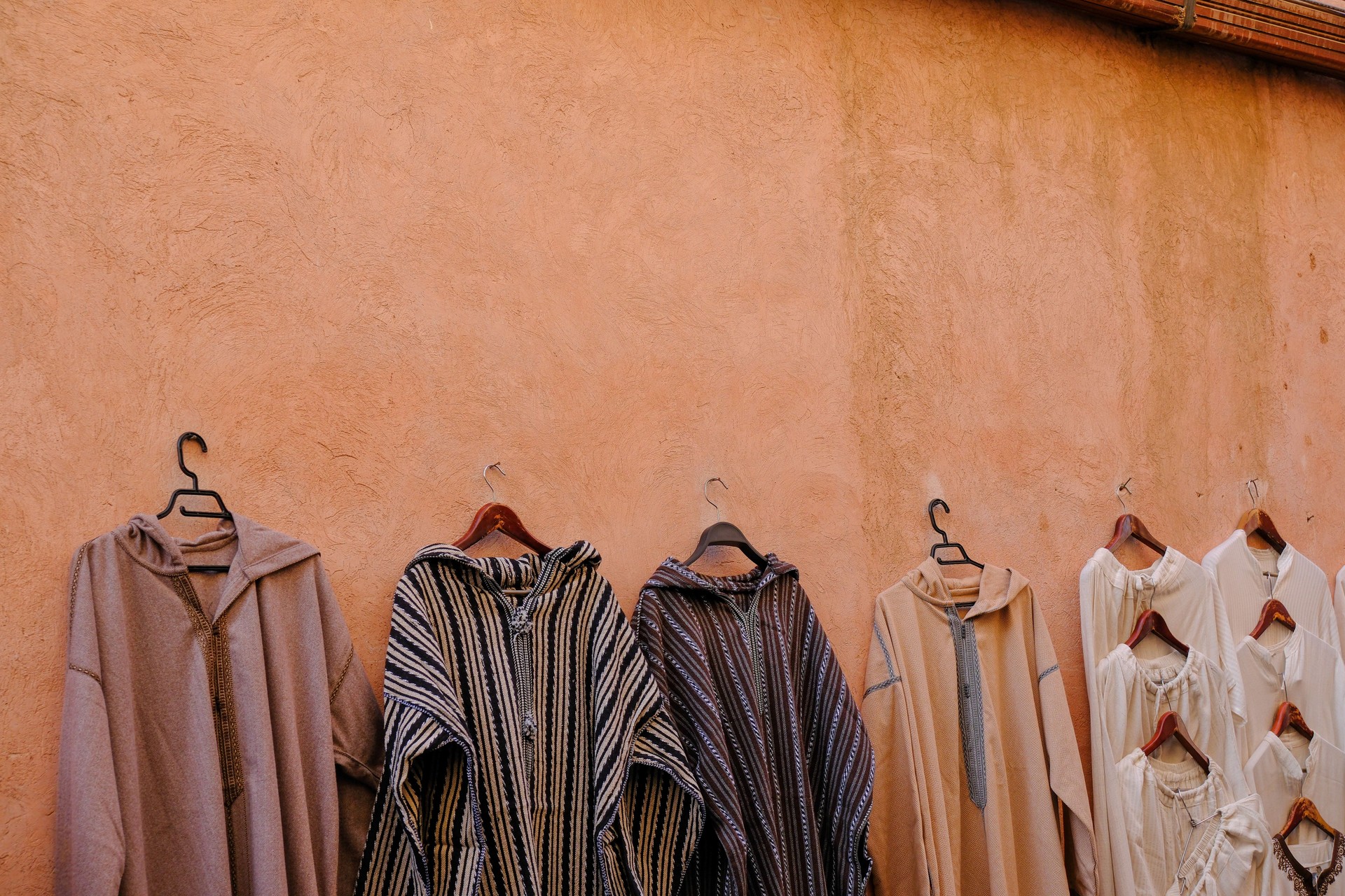 Textile and clothing products on display in a Moroccan market stall with colorful fabrids and dyed materials and shoes